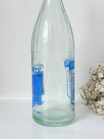 vintage french lemonade bottle la pétillante blue label on white surface with hydrangea flowers