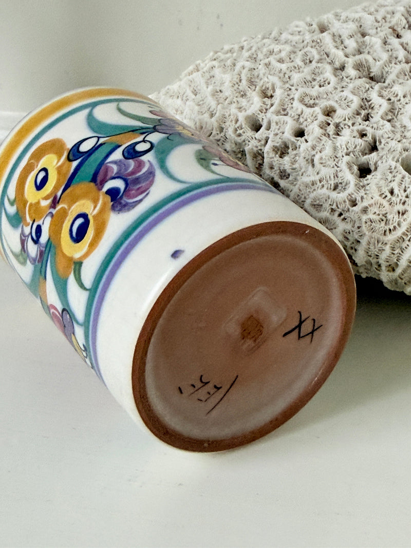 Vintage Poole Pottery pen pot with colourful floral design photographed on a white surface