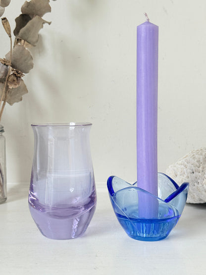 Blue Bormioli Rocco glass candlestick and lilac glass vase photographed on a white surface