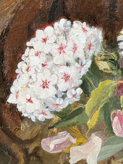 Close-up of a painted floral still life showing a cluster of white blossoms with pink centers, green leaves, and a dark brown background.