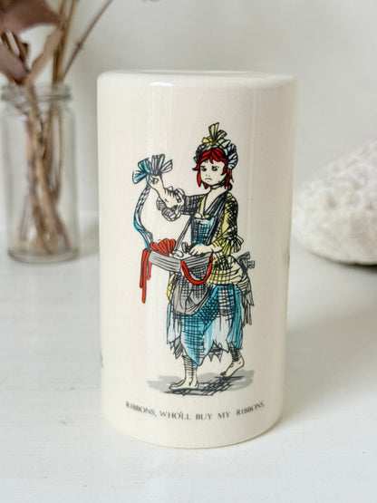 Vintage ceramic money box with illustrated figures photographed on a white surface