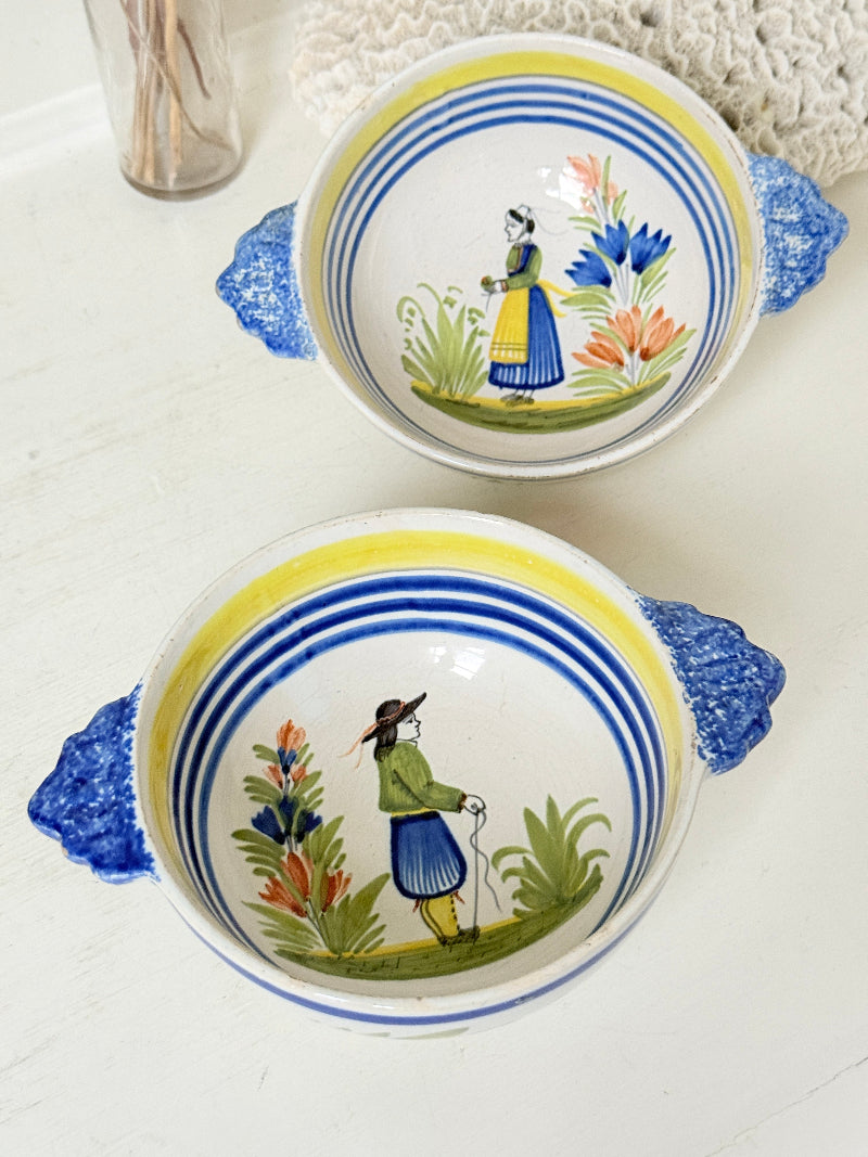 Pair of vintage French Quimper Breton figure bowls with blue handles, photographed on a white surface