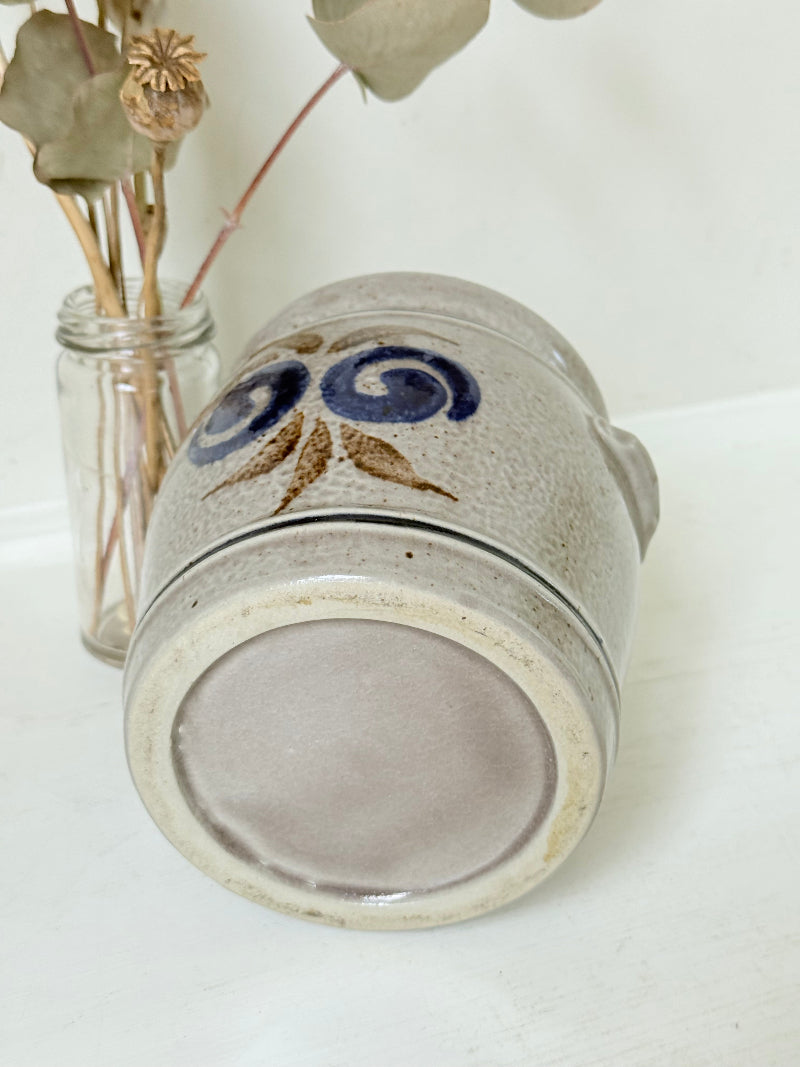 Vintage stoneware confit pot with blue and brown folk art design, photographed on a white surface