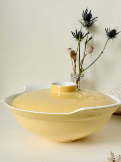 Vintage Poole Pottery lidded serving dish in soft yellow glaze with side handles, photographed on a white surface