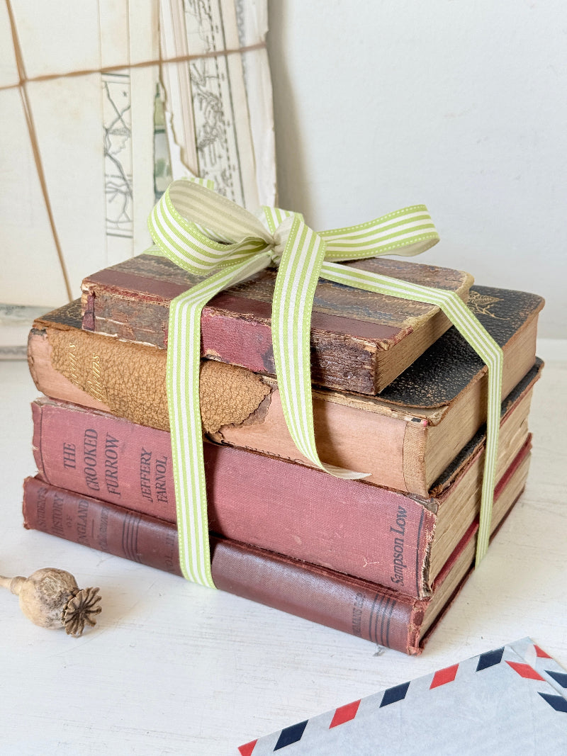 Vintage decorative book bundle with red burgundy cream and green hardback covers tied with green stripe ribbon for interior styling