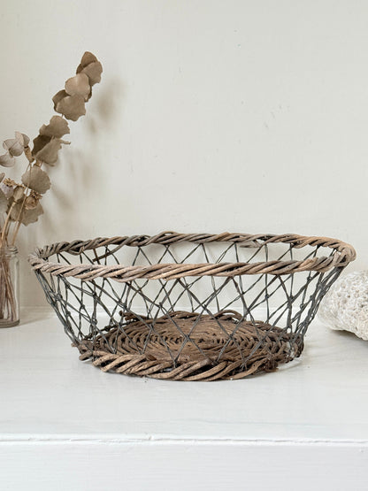 Vintage wicker and wire basket with woven base photographed on a white surface