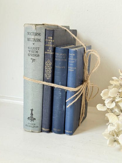 Vintage decorative book bundle in navy, grey, and cream tied with twine, photographed on a white surface
