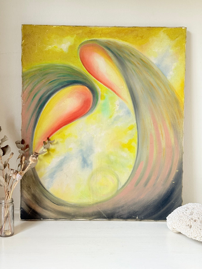 Abstract oil painting on canvas in yellow, pink and grey tones, photographed upright on a white surface beside dried stems.