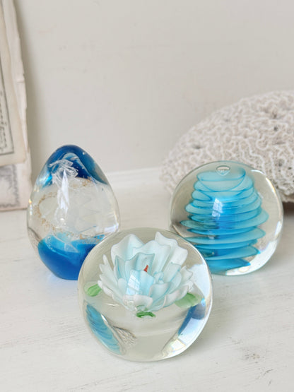Trio of vintage turquoise blue glass paperweights with swirl, ribbed and floral detail in clear coloured glass