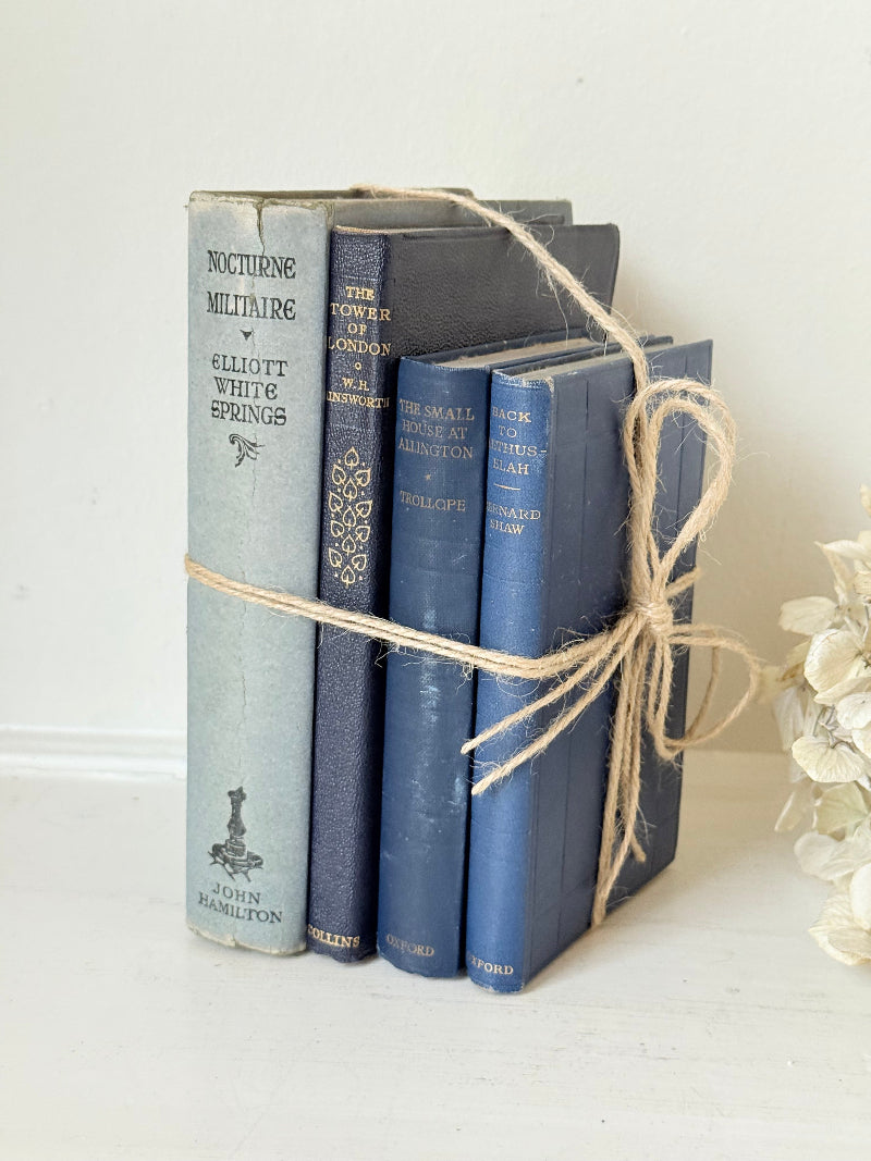 Vintage decorative book bundle in navy, grey, and cream tied with twine, photographed on a white surface