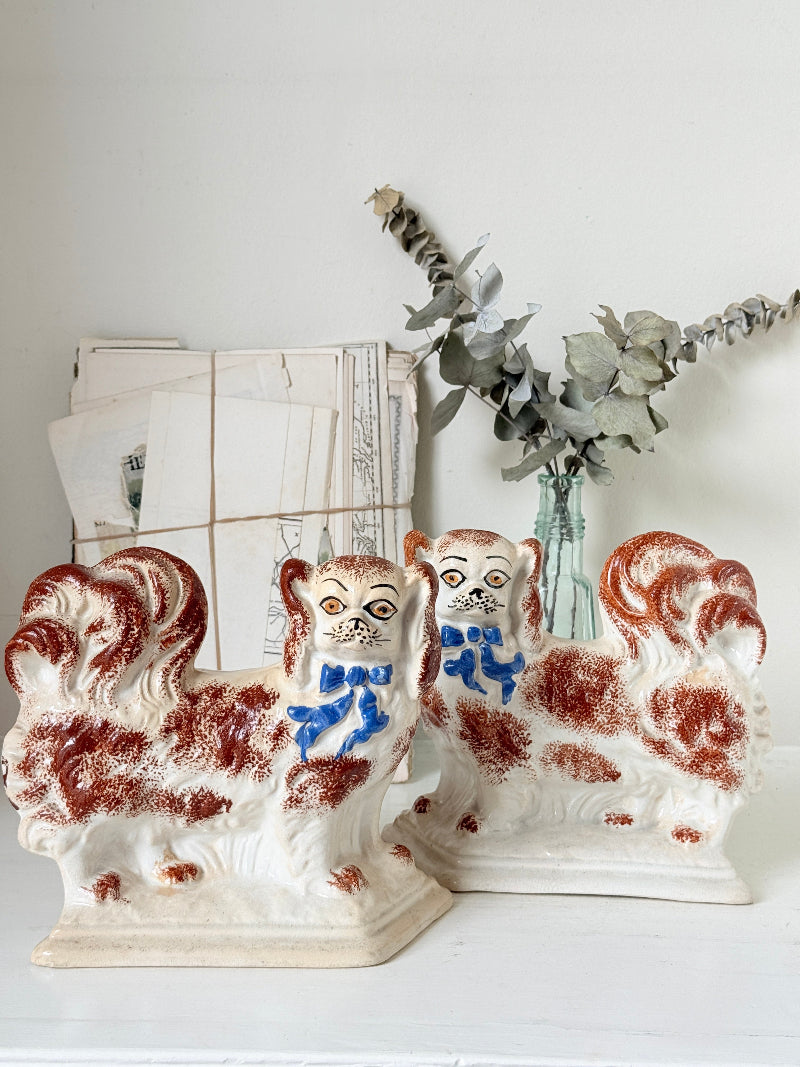 Pair of antique standing Staffordshire Pekingese dogs in rust red and white with blue painted bows