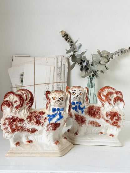 Pair of antique standing Staffordshire Pekingese dogs in rust red and white with blue painted bows