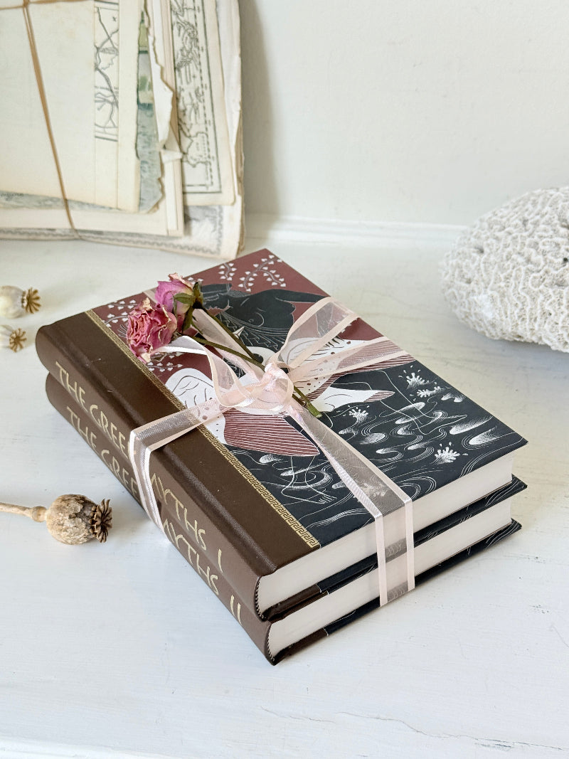 Pair of vintage Greek myths books with brown illustrated covers, pale pink ribbon and dried flower detail for shelf styling