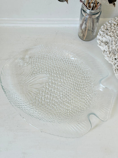 Vintage clear glass fish shaped serving dish with textured scale pattern photographed on a white surface