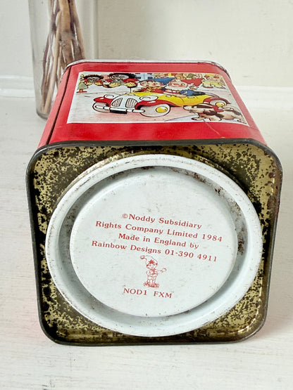 Vintage Noddy money box tin in red with illustrated panels, photographed on a white surface