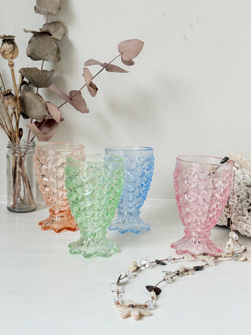Set of 4 vintage pastel pressed glass mermaid goblets with textured scale pattern on a white surface