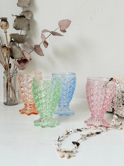 Set of 4 vintage pastel pressed glass mermaid goblets with textured scale pattern on a white surface