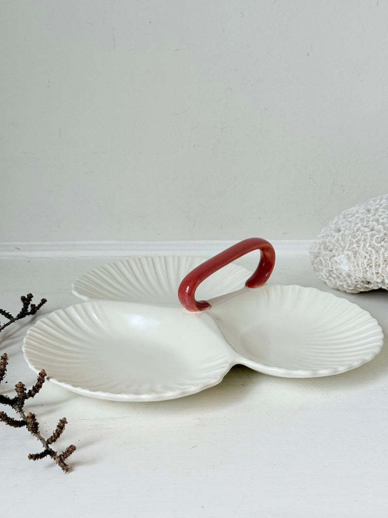 Poole Pottery double scallop hors d’oeuvre dish in white glaze with red handle photographed on a white surface