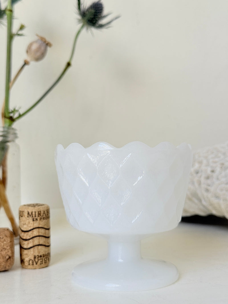 Vintage milk glass footed bowl with scalloped rim and pressed pattern, photographed on a white surface