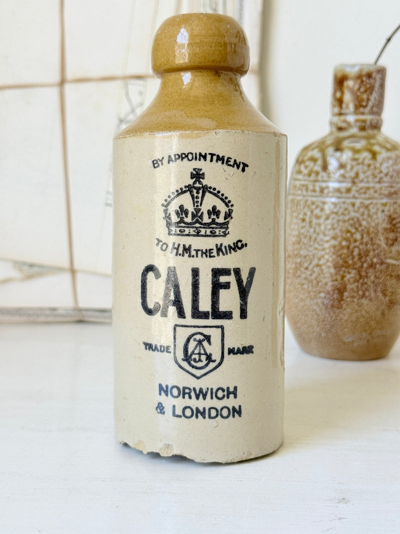 Three antique stoneware bottles, a printed Caley of Norwich and a Portuguese Campos Filhos, photographed on a white surface