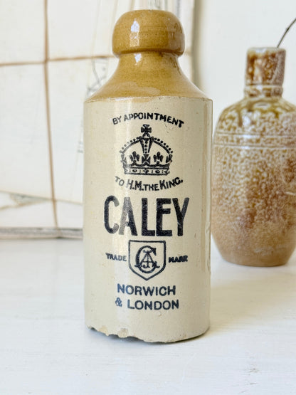 Three antique stoneware bottles, a printed Caley of Norwich and a Portuguese Campos Filhos, photographed on a white surface