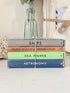 A stack of four vintage hardcover books tied together with twine, placed on a light surface. The spines read &