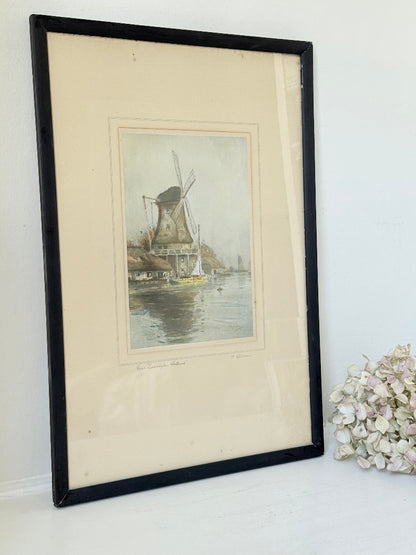 framed print of dutch windmill beside water in holland with reflection photographed on white surface