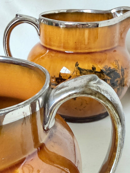 Pair of vintage Ridgways Coaching Days and Coaching Ways treacle jugs in amber brown glaze photographed on a white surface