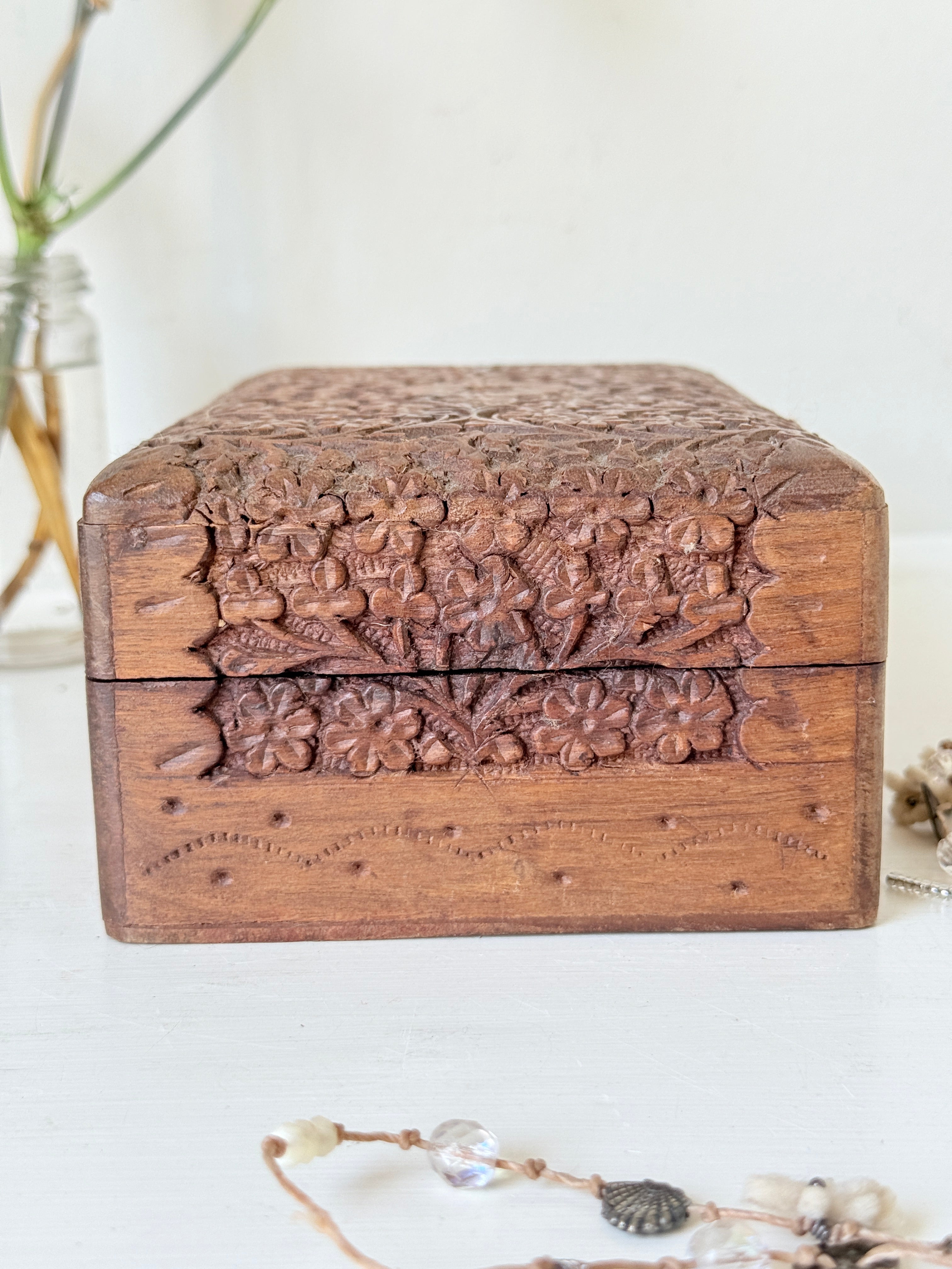 Vintage floral carved wooden jewellery box with detailed hand carved decoration, photographed on a white surface