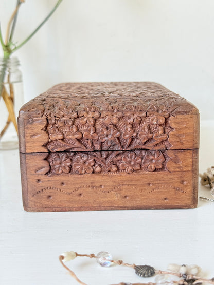 Vintage floral carved wooden jewellery box with detailed hand carved decoration, photographed on a white surface