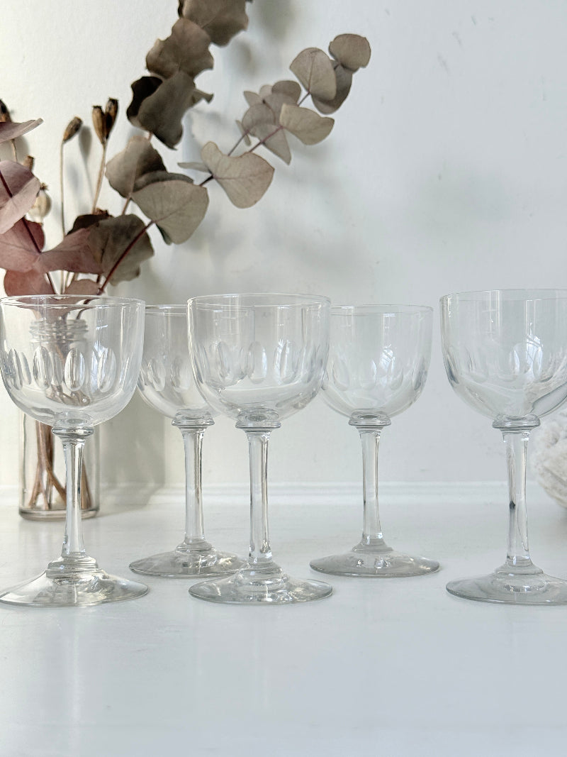 Set of 5 vintage clear glass liqueur glasses with small stems photographed on a white surface