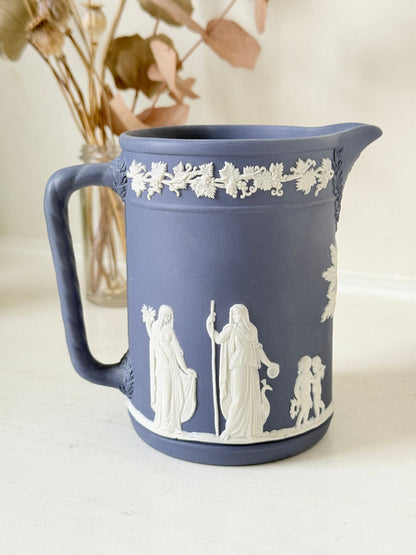 Vintage Wedgwood Portland blue Jasperware jug decorated with white neoclassical figures and a grapevine border, styled with dried stems.