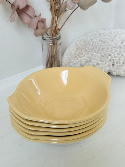 Set of six vintage Poole Pottery lemon bowls in butter yellow glaze photographed on a white surface