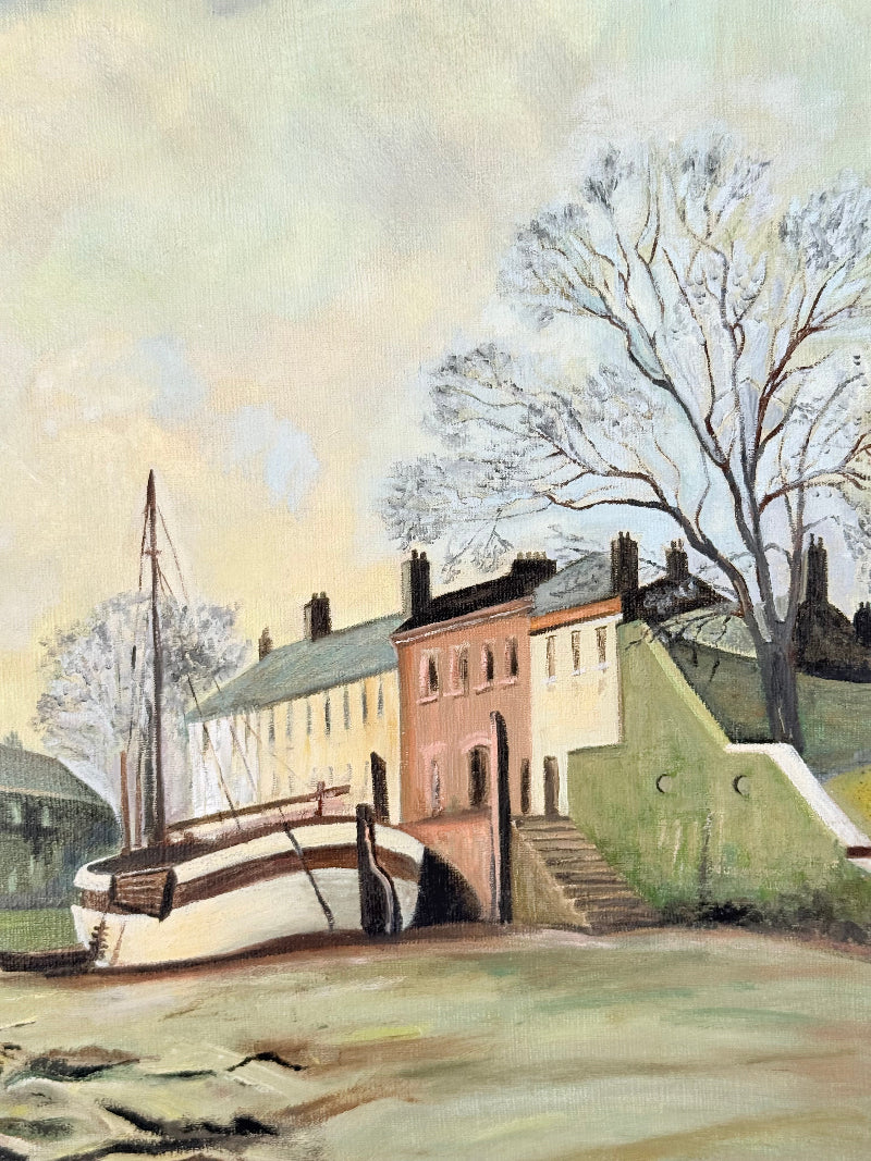 Vintage oil painting on board of a rural village scene with houses, trees, and water, photographed on a white surface