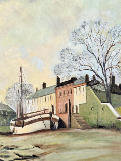 Vintage oil painting on board of a rural village scene with houses, trees, and water, photographed on a white surface