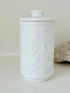French opale glass jar with floral raised design, white vintage milk glass, shown on white background