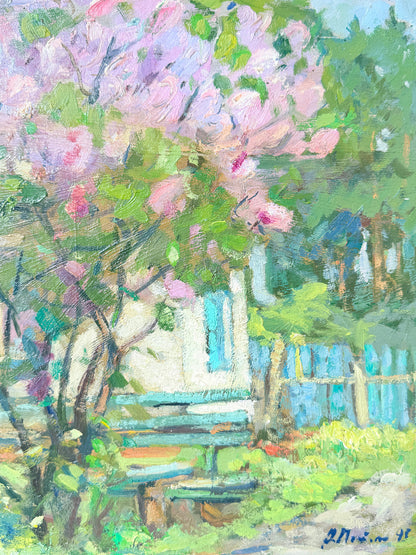 Impressionistic oil painting of a garden scene with pink blossoms, green foliage, a white house, and a blue fence, signed by the artist in the lower right corner.