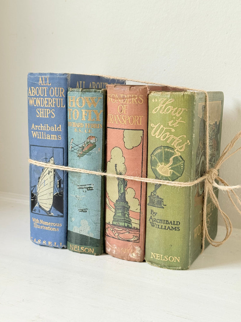 Vintage decorative book bundle in green, blue, and coral with printed lettering, tied with twine, photographed on a white surface