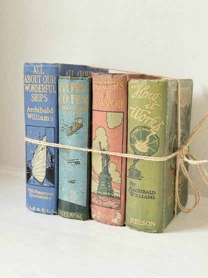 Vintage decorative book bundle in green, blue, and coral with printed lettering, tied with twine, photographed on a white surface