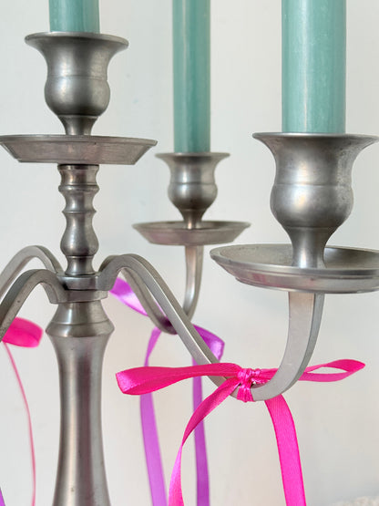 Five arm pewter style metal candelabra with aged silver finish styled with blue green taper candles on white surface