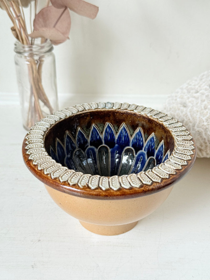 Antique Doulton Lambeth drainer bowl dated 1881 with blue floral interior glaze and drainage holes, photographed on a white surface