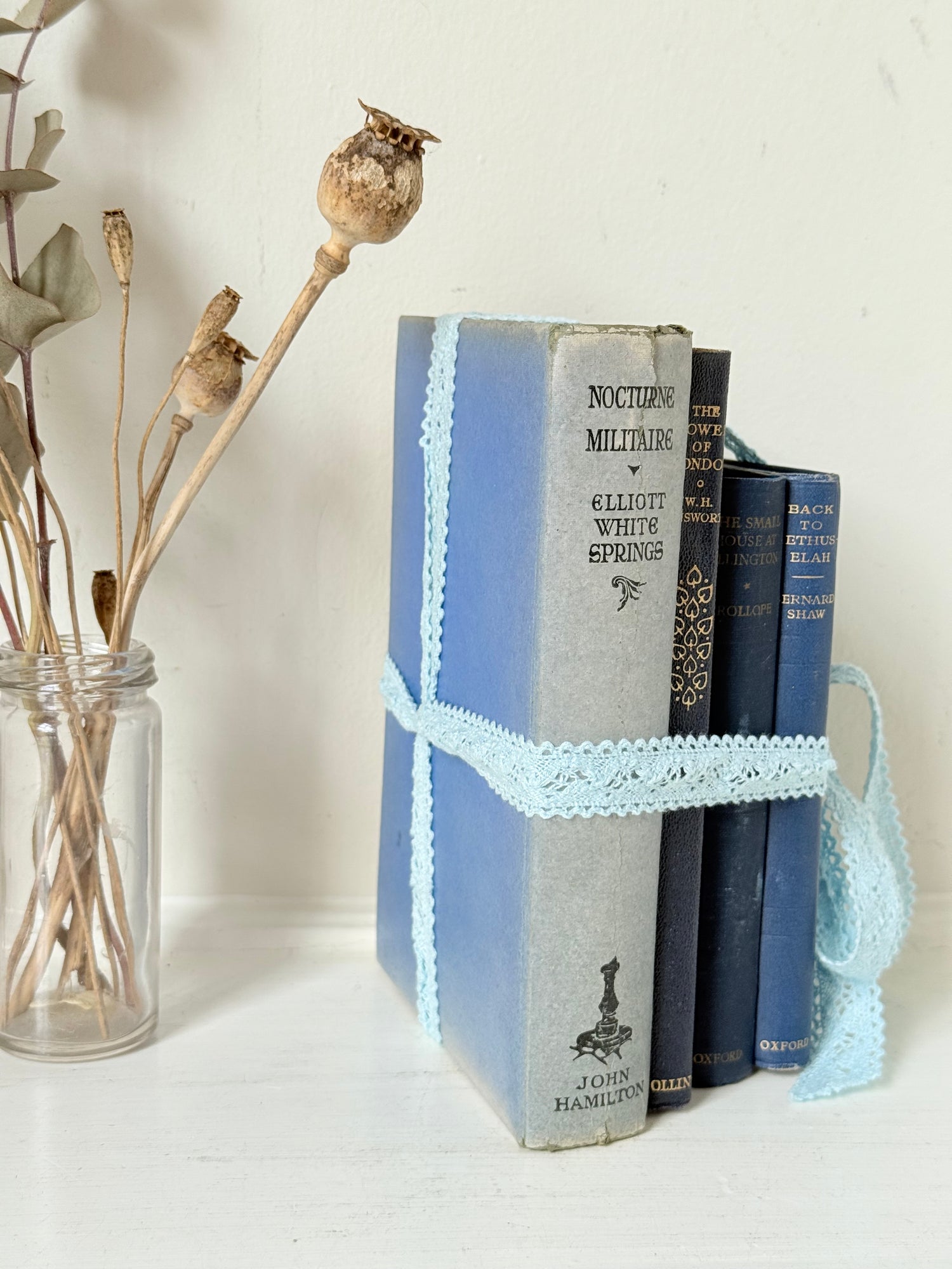 Vintage navy decorative book bundle tied with pale blue lace ribbon, photographed on a white surface