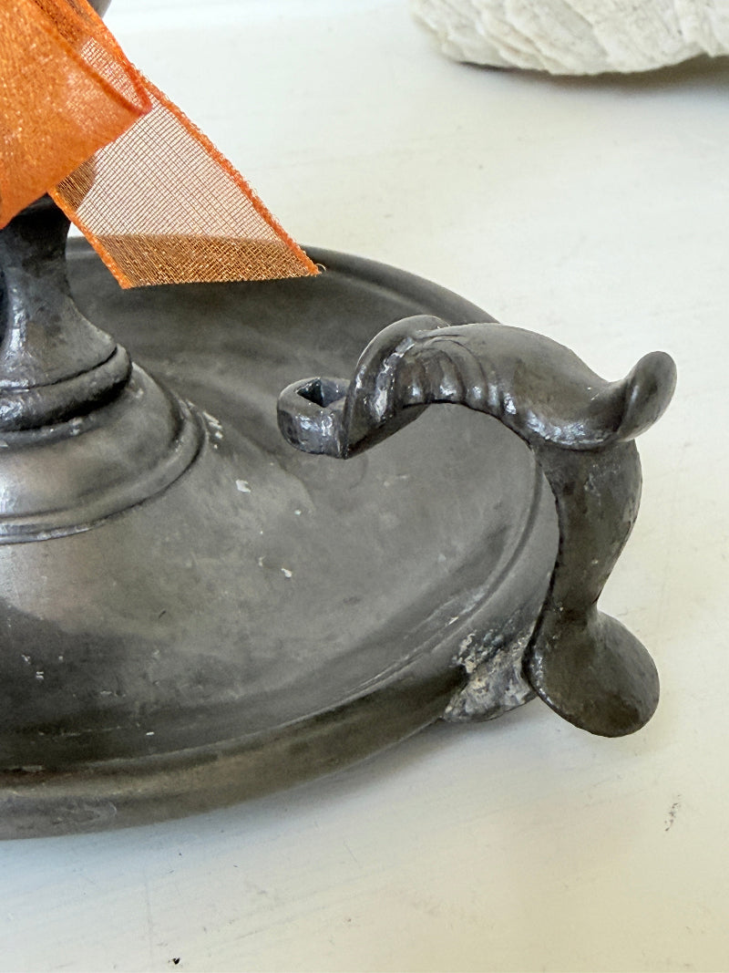 Vintage pewter chamberstick with handle and circular tray, photographed on a white surface