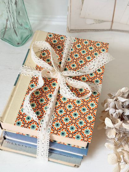 Bundle of vintage cream and blue cloth books with one patterned cover tied with ivory lace for shelf styling