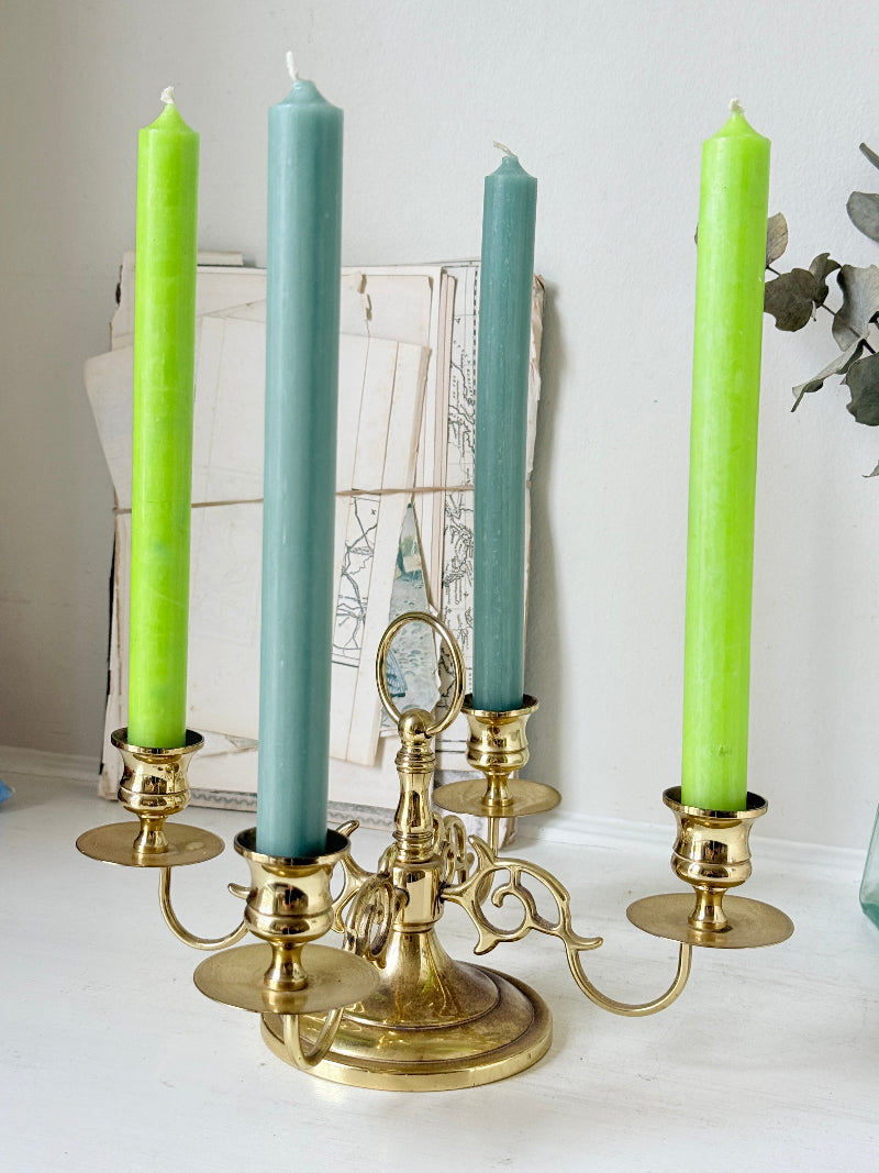 Brass five light candelabra with scrolled arms and a central ring handle on a domed base, photographed on a white surface