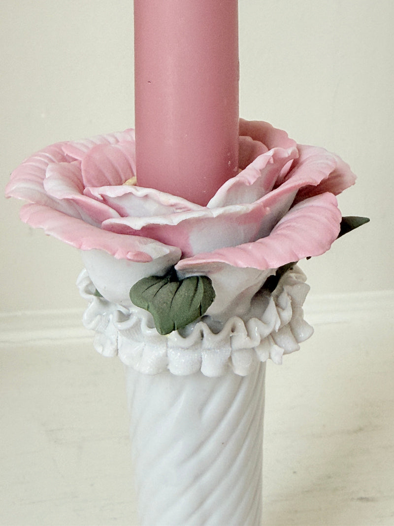 Pair of vintage floral ceramic candlesticks with rose candle cups and pink taper candles styled on a white surface