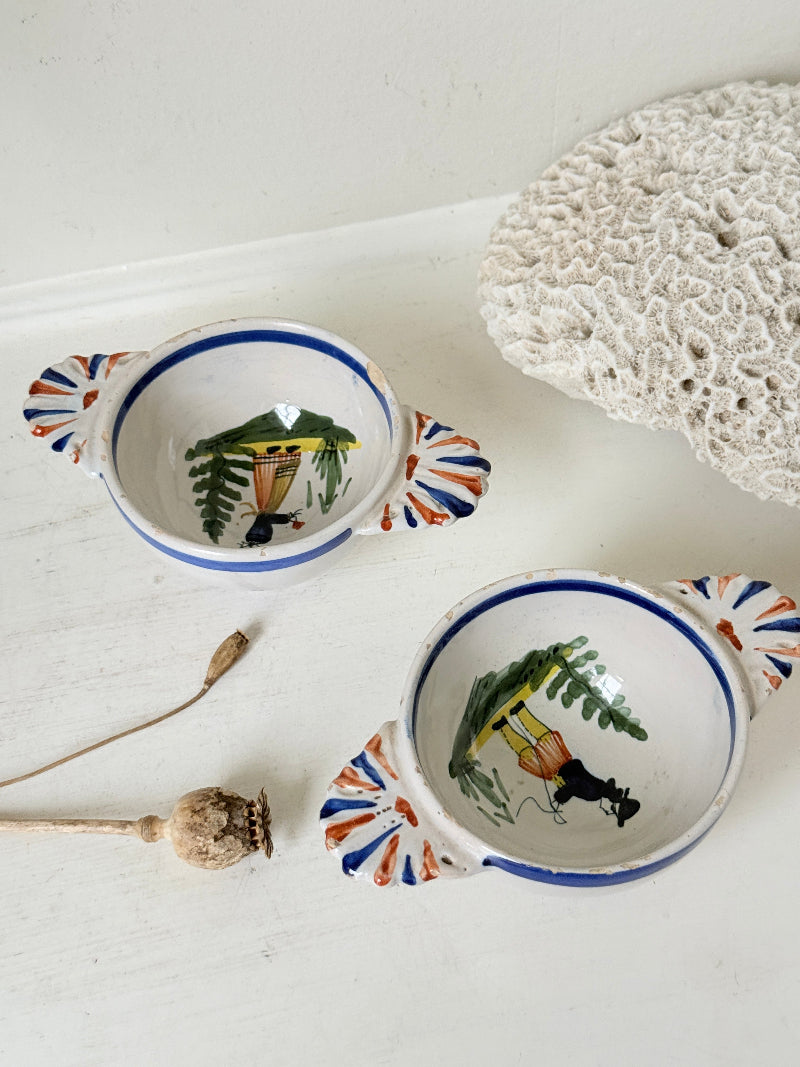 Pair of vintage French Quimper olive bowls with Breton figure and fan handles, photographed on a white surface
