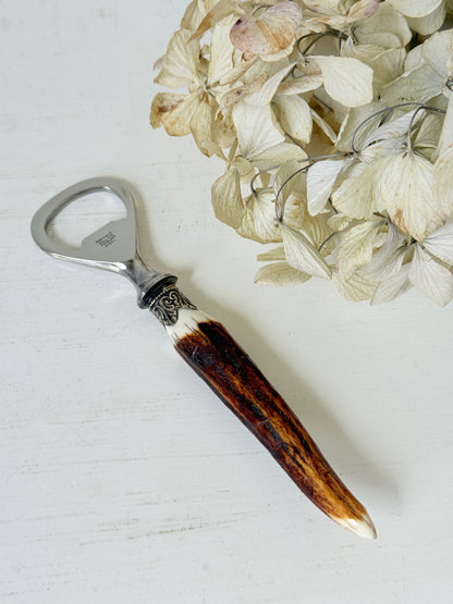 vintage antler handle bottle opener with stainless steel top photographed on white surface