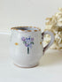vintage studio pottery milk jug with hand painted lilac flowers and ochre rim photographed on white surface