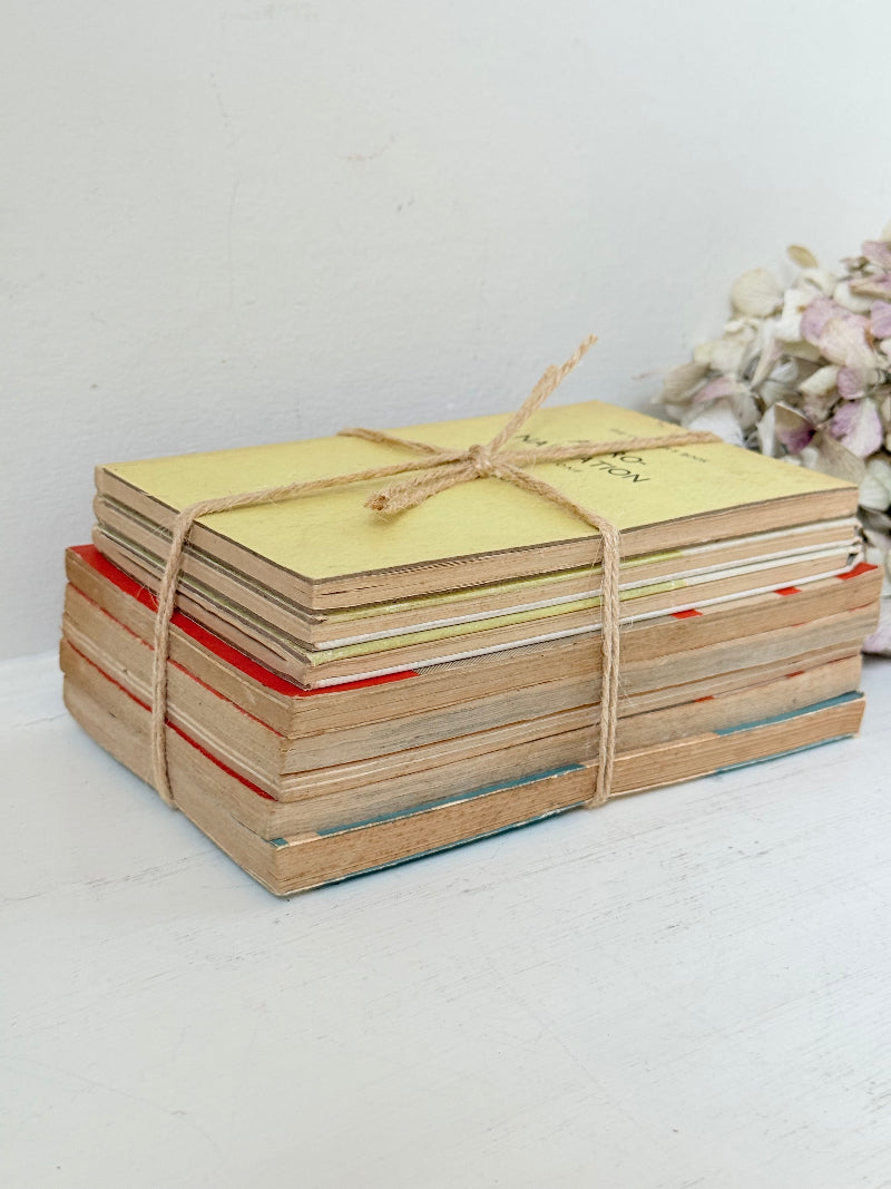 Bundle of vintage Penguin paperback books in orange and cream tones tied with twine, photographed on a white surface